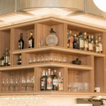 Maßgefertigtes Barregal aus Eichenoptik mit offenen Fächern und LED-Beleuchtung in französischer Brasserie in Wien